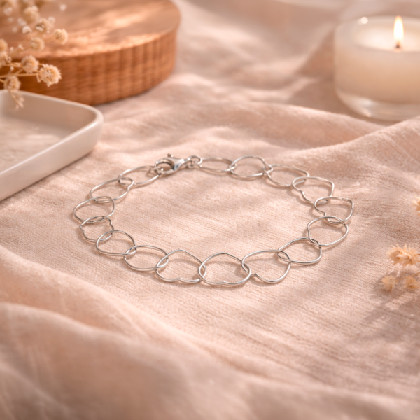 Pulsera plata 925 mujer elegante con eslabones de corazones sobre tela beige estilo delicado