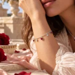 Mujer luciendo la Pulsera Corazones Rojos en plata 925 de Glow Secret, con cinco dijes de corazón, en una escena romántica con rosas rojas.