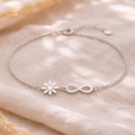 Pulsera plata 925 infinito mujer con flor e infinito sobre tela beige, fotografía lifestyle elegante Glow Secret