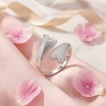 anillo-doble-corazon-brillante-lifestyle Anillo Doble Corazón Brillante en composición lifestyle con flores rosadas