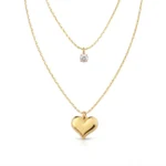 Collar Corazón Dorado Mujer de doble cadena chapado en Oro 18K con recubrimiento PVD, usado por una mujer en fotografía editorial premium de la colección Gold Essential.