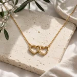 Collar Doble Corazón Editorial Collar Doble Corazón Chapado en Oro 18K sobre escenario editorial de la colección Gold Essential.