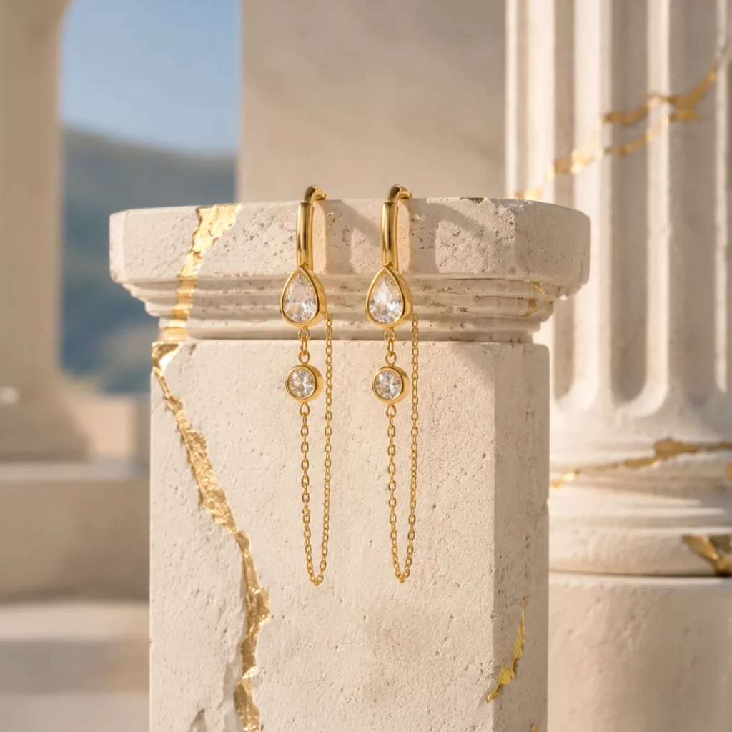 Aros Dorados Colgantes Gold Essential de Glow Secret sobre pedestal inspirado en la arquitectura griega.