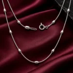 Collar Largo de Plata 925 Mujer sobre satén burdeos, con cadena veneciana y detalles ovalados pulidos de la colección ICONIC.