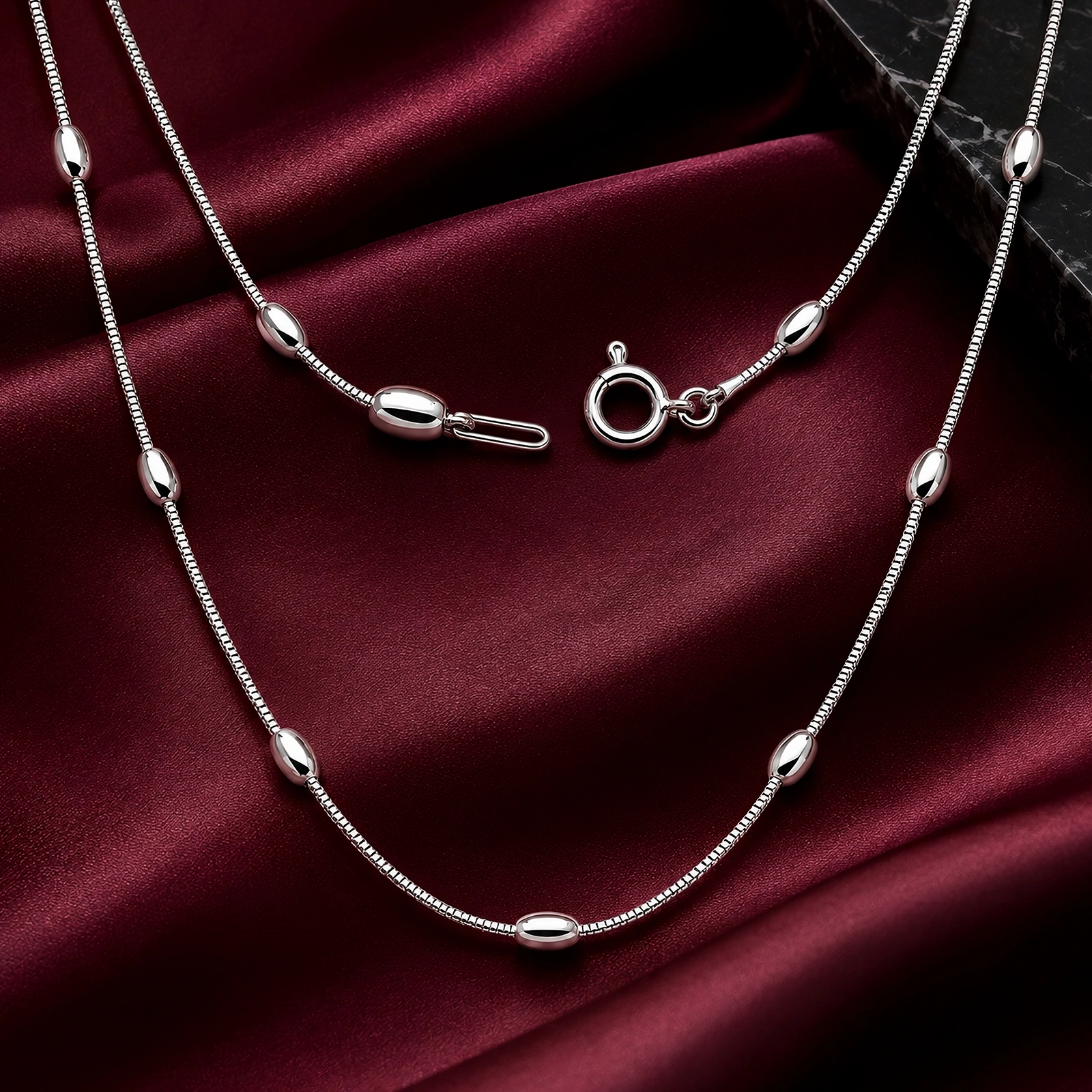 Collar Largo de Plata 925 Mujer sobre satén burdeos, con cadena veneciana y detalles ovalados pulidos de la colección ICONIC.